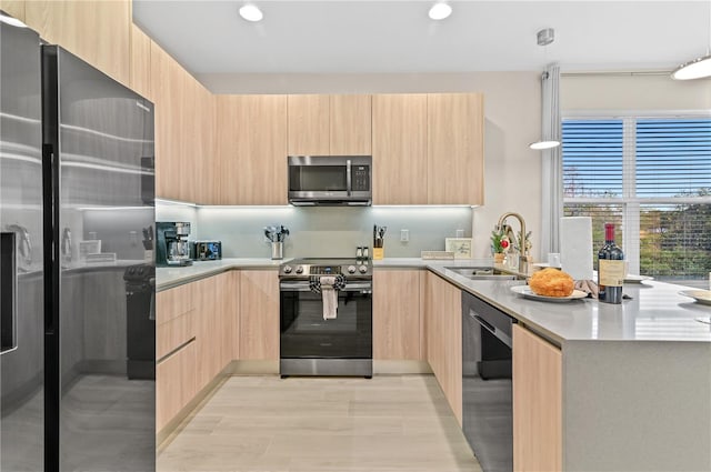 kitchen featuring stainless steel appliances, light brown cabinets, and decorative light fixtures