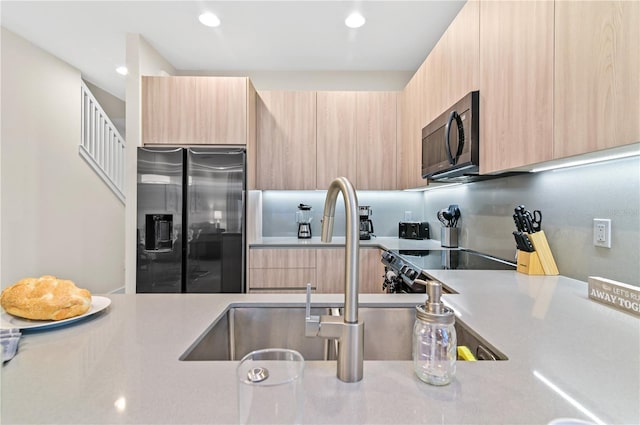 kitchen featuring stainless steel refrigerator with ice dispenser, stove, sink, and light brown cabinets