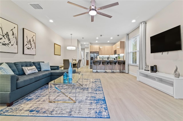 living room featuring ceiling fan and light hardwood / wood-style floors