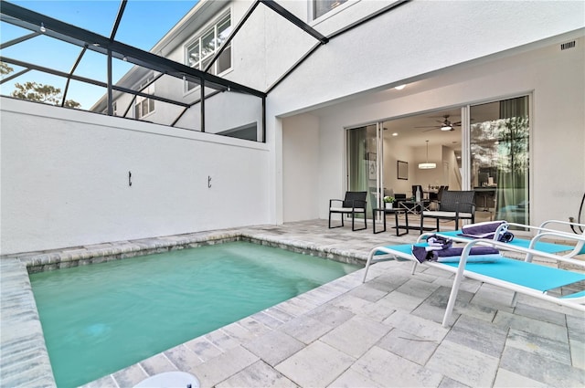 view of swimming pool with a patio area, ceiling fan, and glass enclosure