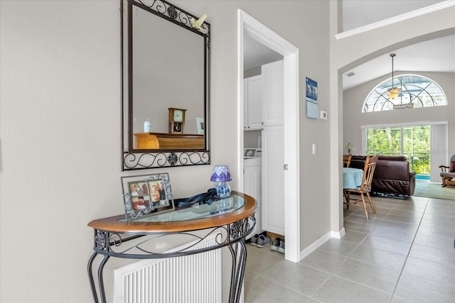 hallway with washer / clothes dryer, light tile patterned flooring, and high vaulted ceiling