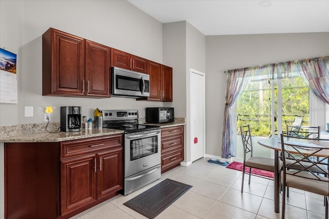 kitchen featuring light stone countertops, vaulted ceiling, stainless steel appliances, and light tile patterned flooring