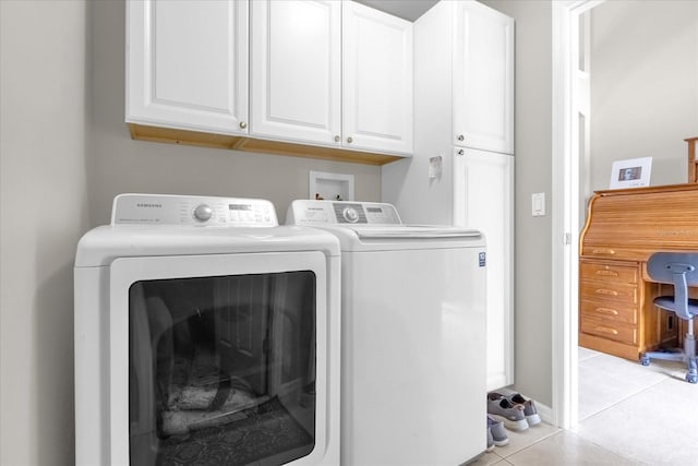 clothes washing area with cabinets, washer and clothes dryer, and light tile patterned floors