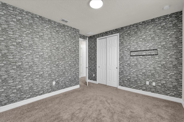 carpeted empty room with a textured ceiling