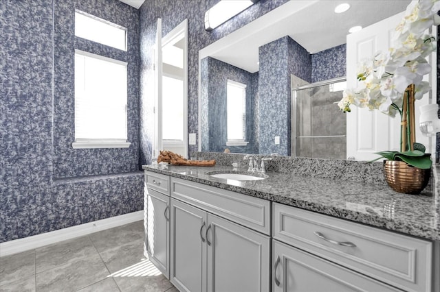 bathroom with tile patterned floors, a healthy amount of sunlight, a shower with shower door, and vanity