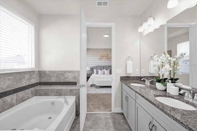 bathroom with tile patterned flooring, vanity, a bathing tub, and a wealth of natural light