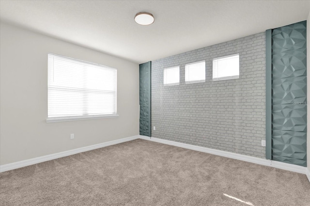 spare room featuring plenty of natural light, brick wall, and carpet