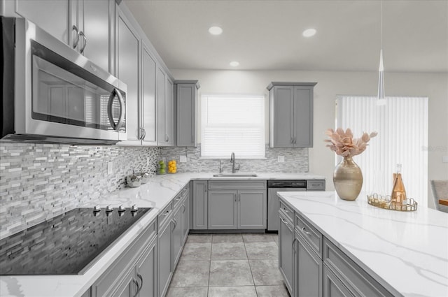 kitchen featuring sink, appliances with stainless steel finishes, gray cabinetry, backsplash, and light stone countertops