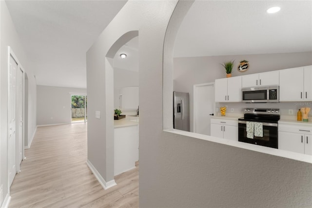 kitchen with white cabinetry, light wood-type flooring, vaulted ceiling, and appliances with stainless steel finishes