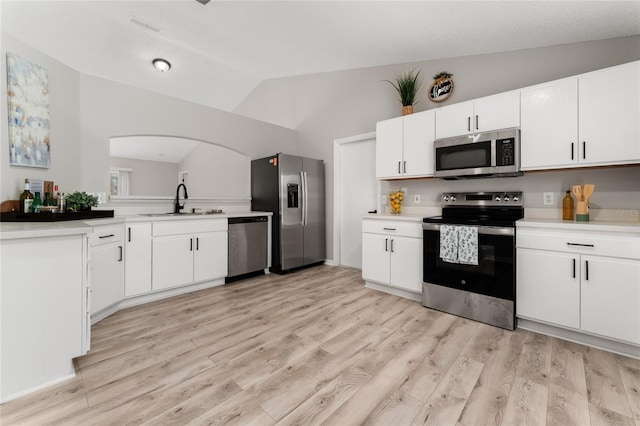 kitchen featuring lofted ceiling, sink, white cabinetry, stainless steel appliances, and light wood-type flooring