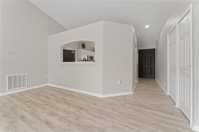 unfurnished room featuring lofted ceiling and light hardwood / wood-style flooring