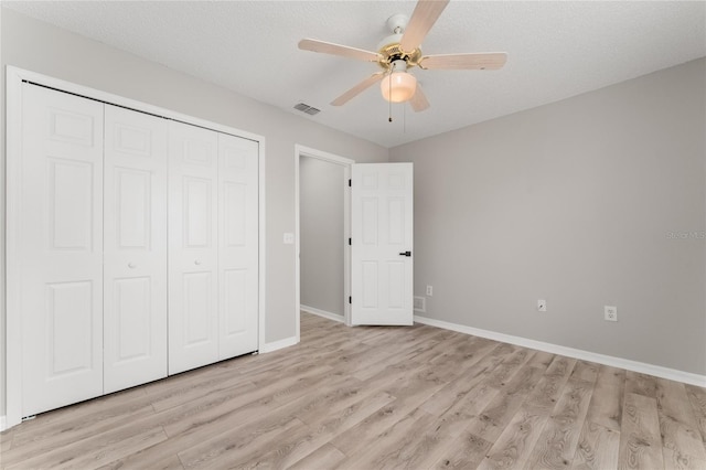 unfurnished bedroom featuring ceiling fan, a textured ceiling, light hardwood / wood-style floors, and a closet