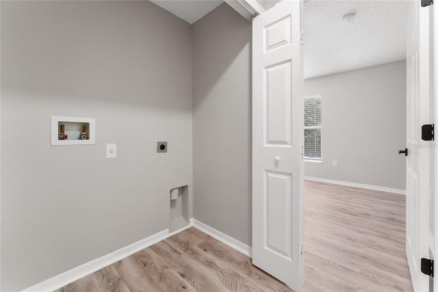 laundry room featuring a textured ceiling, hookup for a washing machine, light hardwood / wood-style flooring, and electric dryer hookup