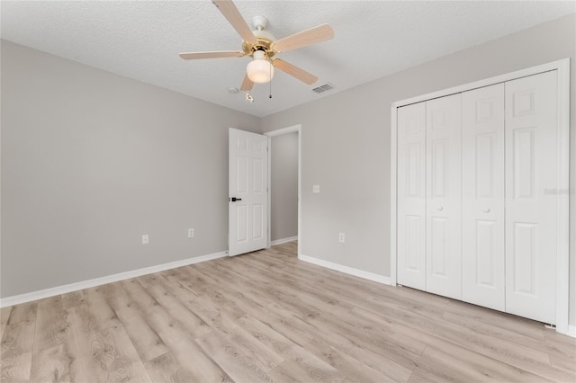 unfurnished bedroom featuring ceiling fan, a closet, light hardwood / wood-style flooring, and a textured ceiling