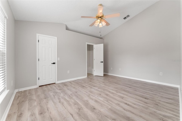 unfurnished bedroom with lofted ceiling, multiple windows, ceiling fan, and light wood-type flooring