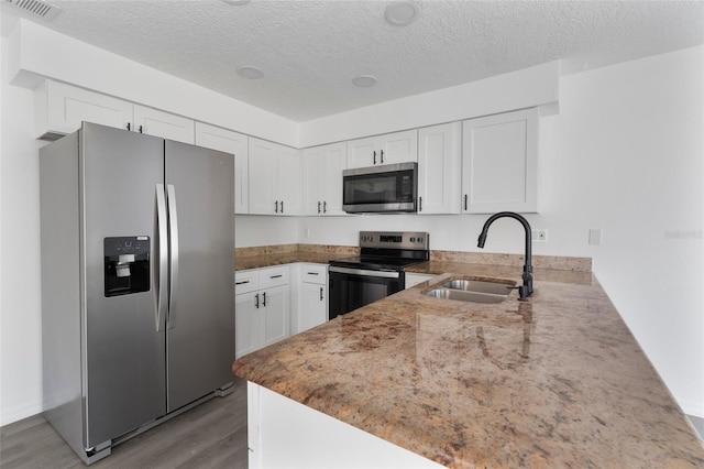 kitchen with white cabinetry, stainless steel appliances, kitchen peninsula, and sink