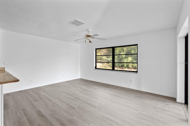 unfurnished living room with ceiling fan, a textured ceiling, and light wood-type flooring