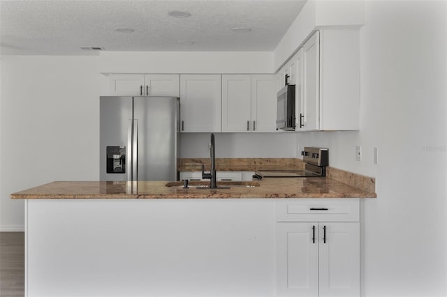 kitchen with white cabinetry, sink, light stone counters, kitchen peninsula, and stainless steel appliances