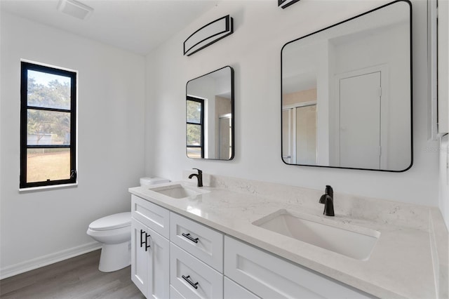 bathroom with hardwood / wood-style flooring, vanity, toilet, and an enclosed shower