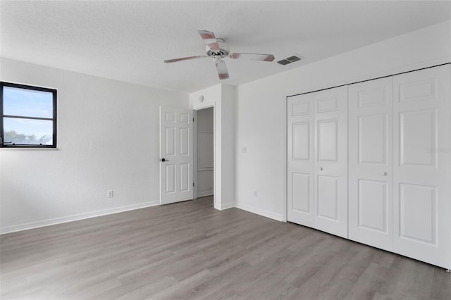 unfurnished bedroom with ceiling fan, a closet, a textured ceiling, and light wood-type flooring