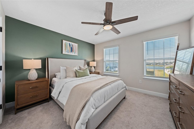 bedroom featuring ceiling fan, light colored carpet, and a textured ceiling