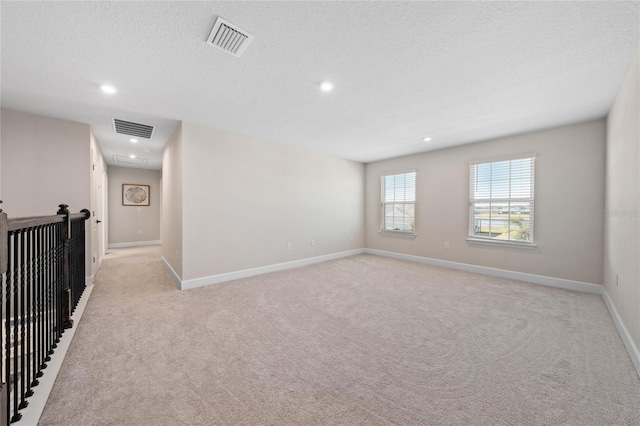 empty room featuring light colored carpet and a textured ceiling