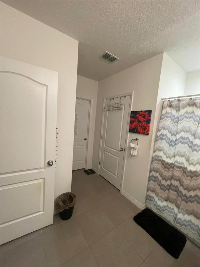 corridor with tile patterned floors and a textured ceiling