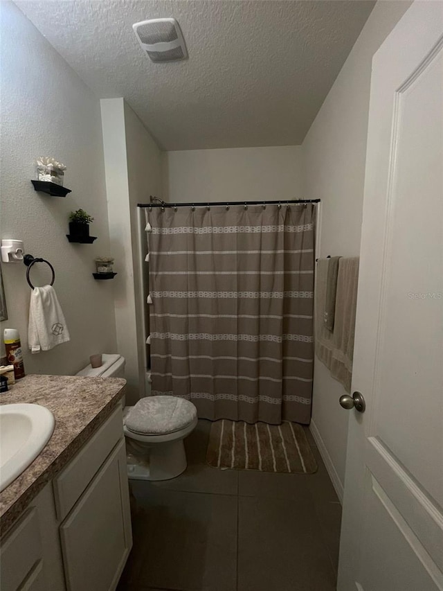 bathroom featuring toilet, a textured ceiling, vanity, curtained shower, and tile patterned flooring