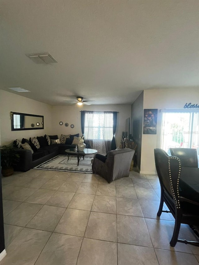 tiled living room featuring a textured ceiling and ceiling fan