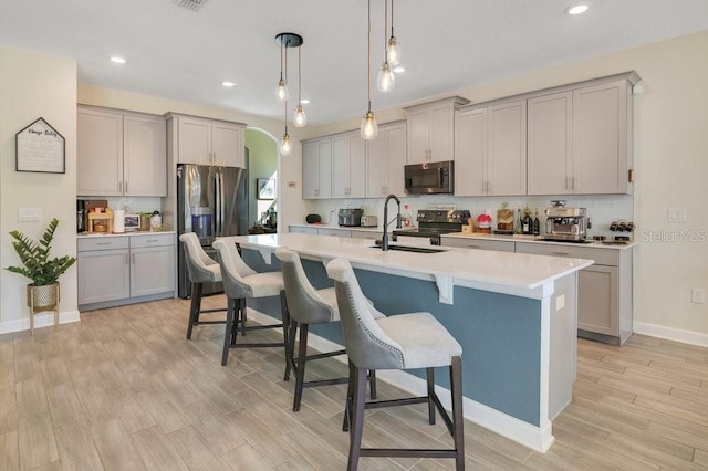 kitchen featuring an island with sink, appliances with stainless steel finishes, and gray cabinetry