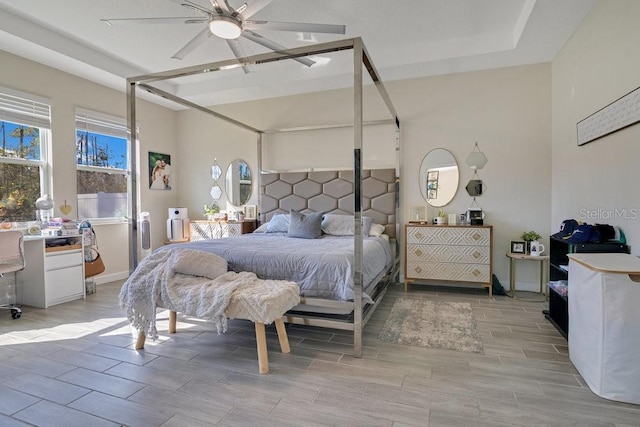 bedroom featuring wood tiled floor, baseboards, ceiling fan, and a raised ceiling