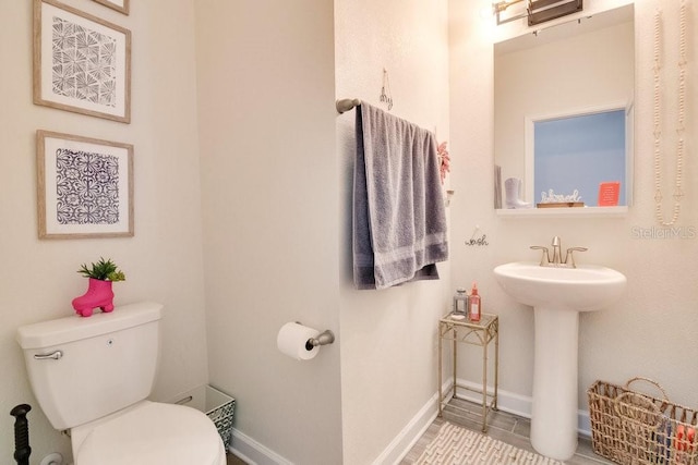 bathroom featuring a sink, toilet, and baseboards