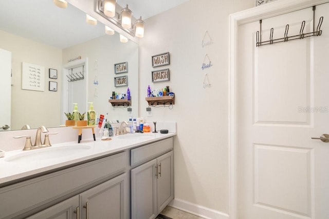 bathroom featuring double vanity, baseboards, and a sink