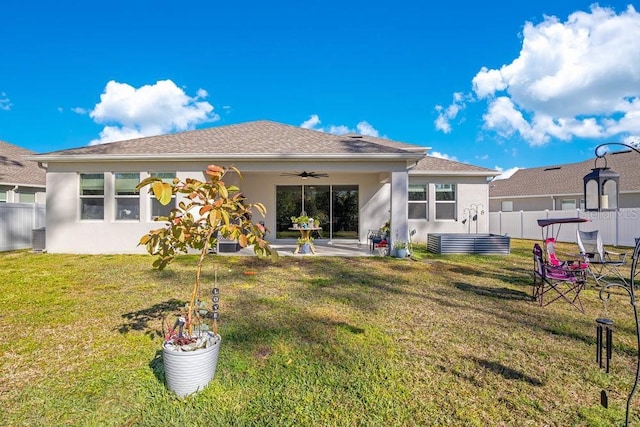 rear view of property featuring fence, a ceiling fan, a yard, stucco siding, and a patio area