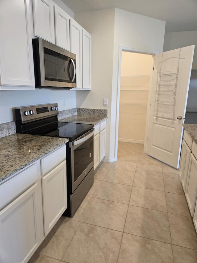 kitchen featuring white cabinetry, stainless steel appliances, light stone countertops, and light tile patterned floors