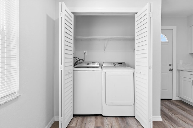 clothes washing area featuring washing machine and dryer and light hardwood / wood-style flooring