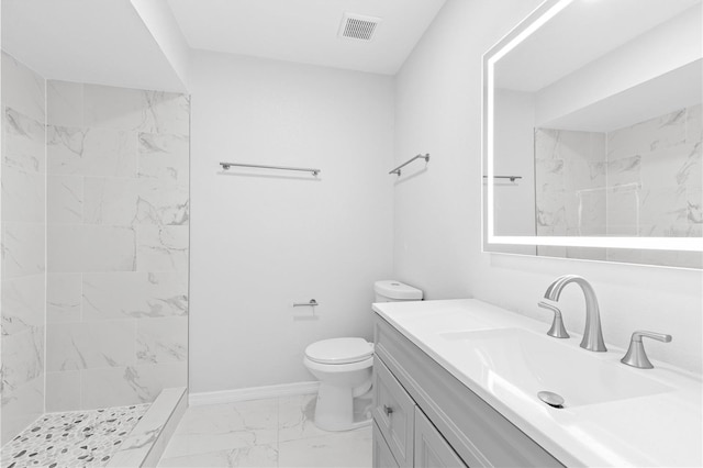 bathroom featuring tiled shower, vanity, and toilet