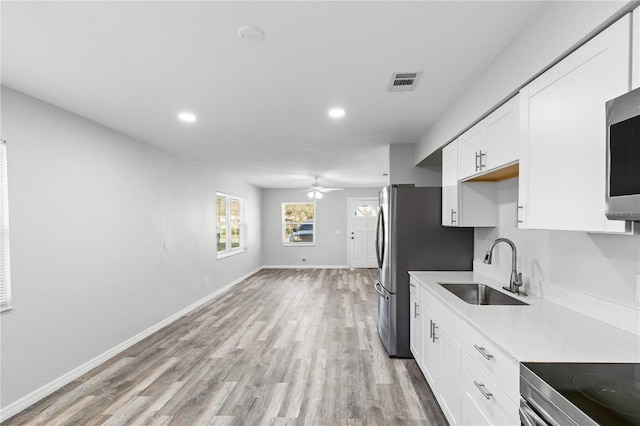 kitchen with white cabinetry, sink, ceiling fan, and light hardwood / wood-style floors