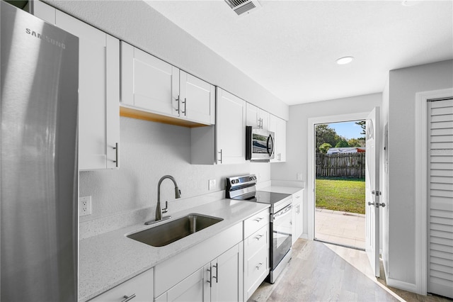 kitchen featuring stainless steel appliances, sink, white cabinets, and light hardwood / wood-style flooring