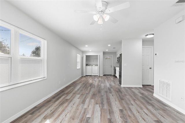 unfurnished living room with ceiling fan, separate washer and dryer, and light wood-type flooring