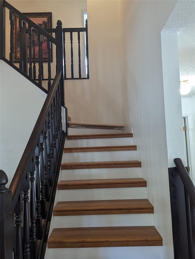 staircase featuring a textured ceiling