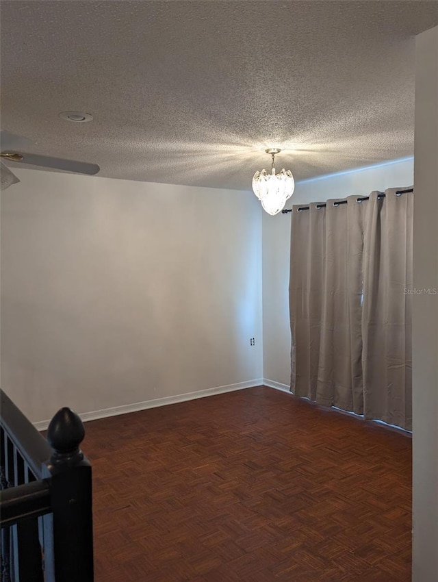 unfurnished room with dark parquet flooring, ceiling fan with notable chandelier, and a textured ceiling