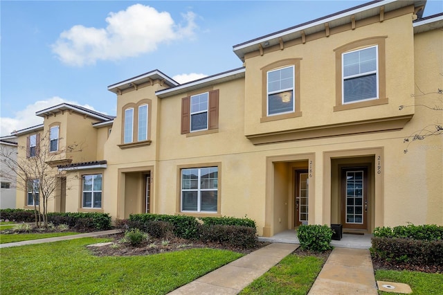 view of property featuring a front lawn and stucco siding