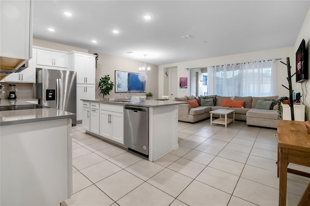 kitchen with appliances with stainless steel finishes, an island with sink, light tile patterned flooring, and white cabinets