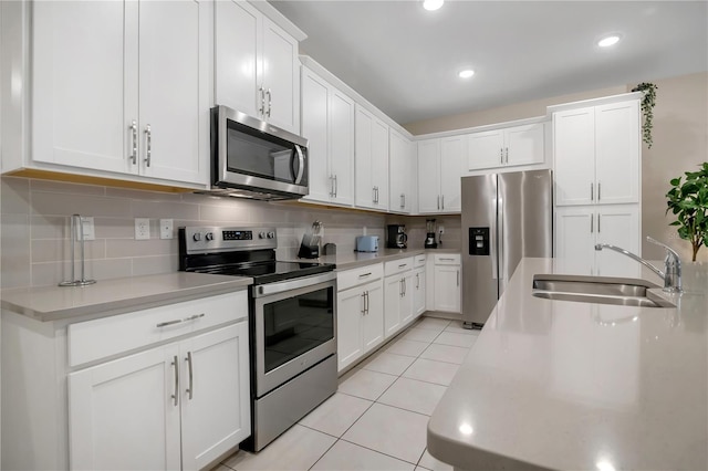 kitchen featuring light tile patterned floors, appliances with stainless steel finishes, a sink, and decorative backsplash