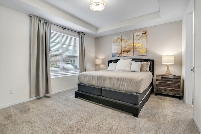 bedroom featuring a raised ceiling, carpet flooring, and baseboards