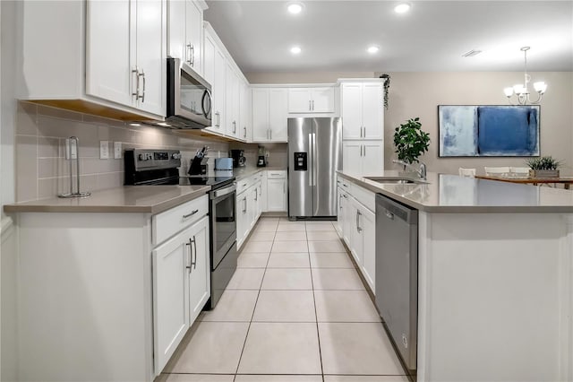 kitchen with light tile patterned floors, tasteful backsplash, appliances with stainless steel finishes, white cabinets, and a sink