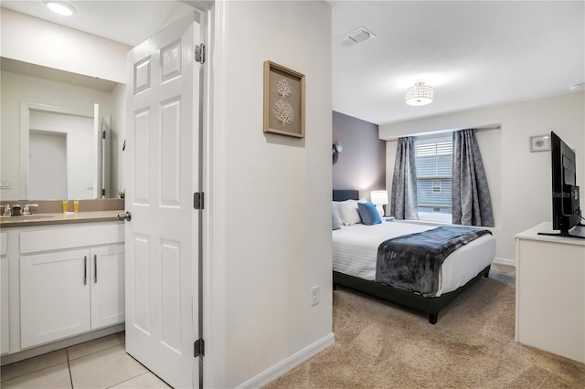 bedroom with light tile patterned floors, visible vents, light carpet, a sink, and baseboards