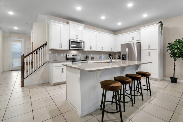 2186 Fleming Mist Pl, Kissimmee, FL 34747 - kitchen featuring stainless steel appliances, backsplash, a center island with sink, light countertops, and a kitchen bar