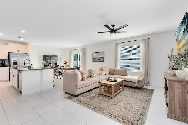 living room featuring ceiling fan, sink, and light tile patterned floors